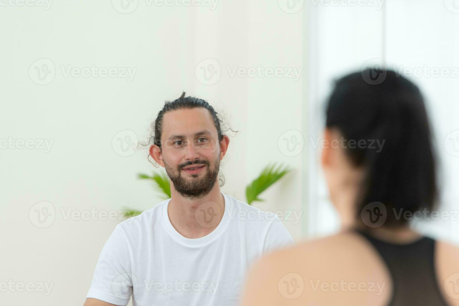 ung kvinna och manlig idrottare Sammanträde resten på yoga mattor och dricka vatten. de är ser på varje Övrig och leende foto