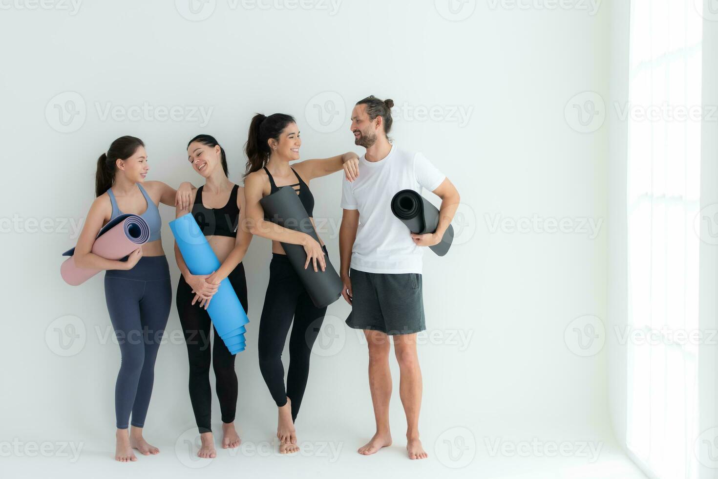 en grupp av kvinna och manlig idrottare stod och chattade i godo i de studio innan början med de yoga klass. foto