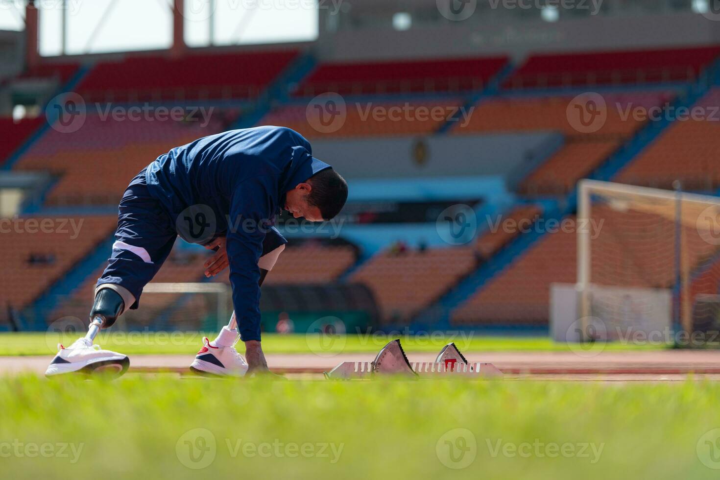 Inaktiverad atletisk man stretching och uppvärmningen upp innan löpning på stadion Spår foto