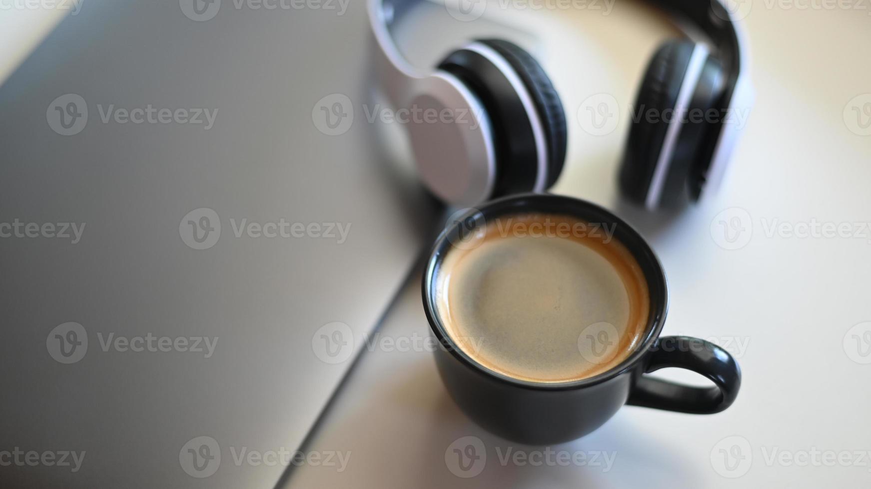 ovanifrån skott av kaffemugg med bärbar dator och hörlurar placerade på ett bord i ett café. foto