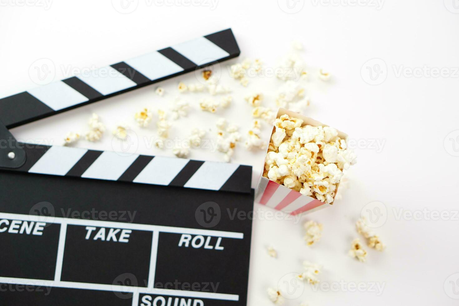 fokus av popcorn och fläck clapperboard eller film skiffer svart Färg på vit bakgrund. bio industri, video produktion och filma begrepp. foto
