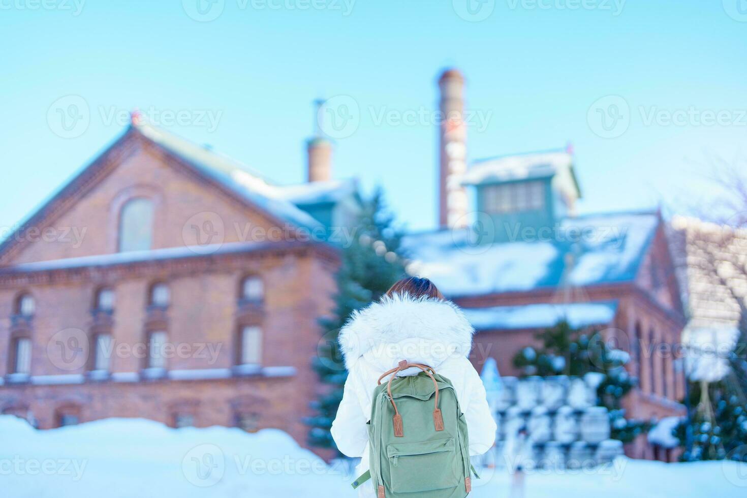 kvinna turist besöker i sapporo, resande i Tröja ser sapporo öl museum med snö i vinter- säsong. landmärke och populär för attraktioner i Hokkaido, japan. resa och semester begrepp foto