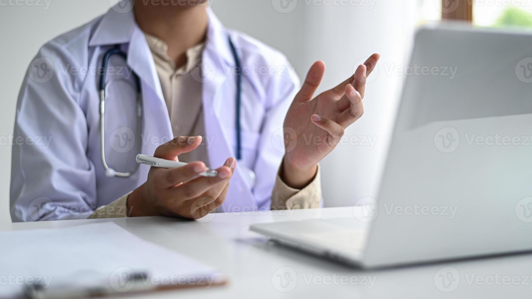 läkare ger medicinsk rådgivning med videoströmning med en bärbar dator placerad framför bordet. foto
