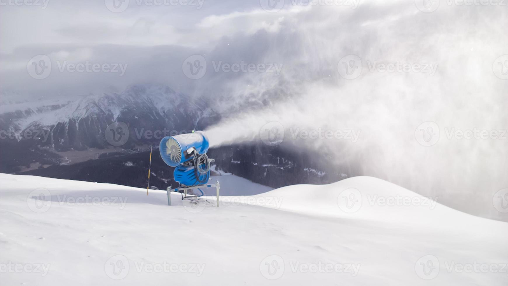 kanon skjuter snö i schweiziska alpernas turistområde foto
