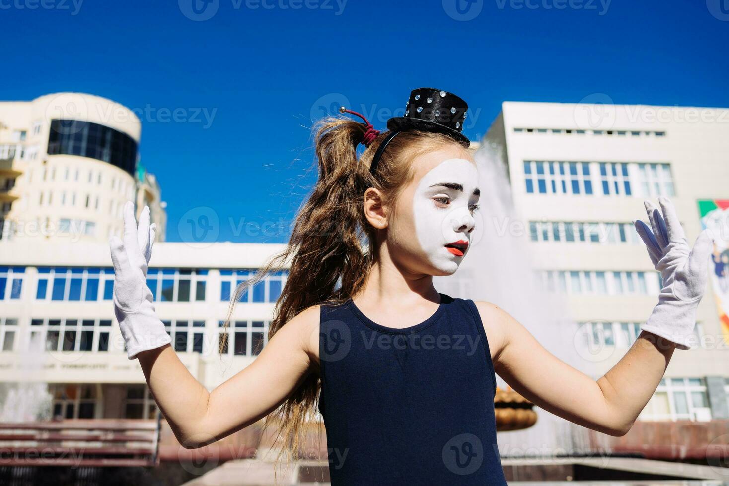 liten mima flicka visar pantomim på de gata foto