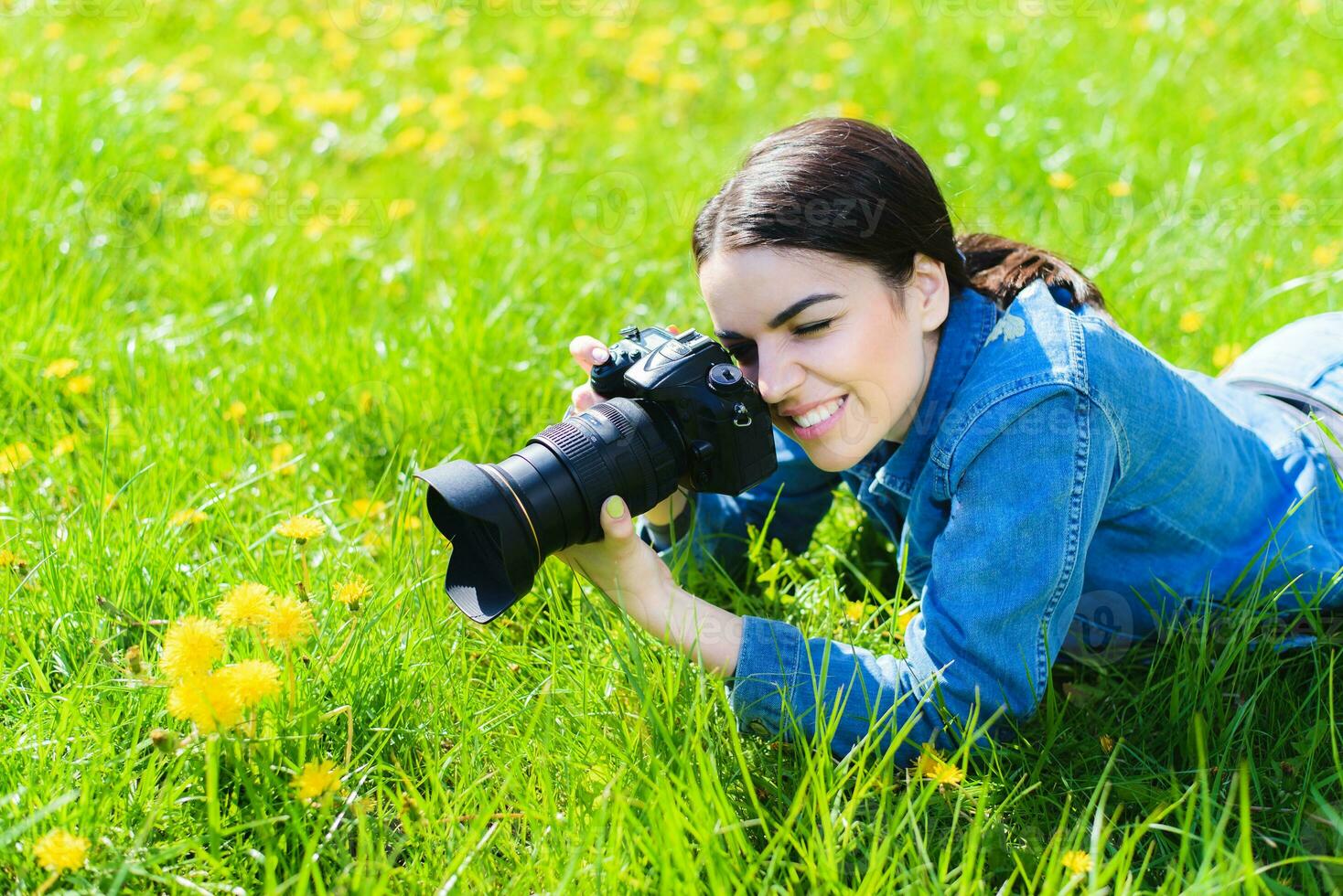 attraktiv flicka i en äng tar bilder av blommor foto