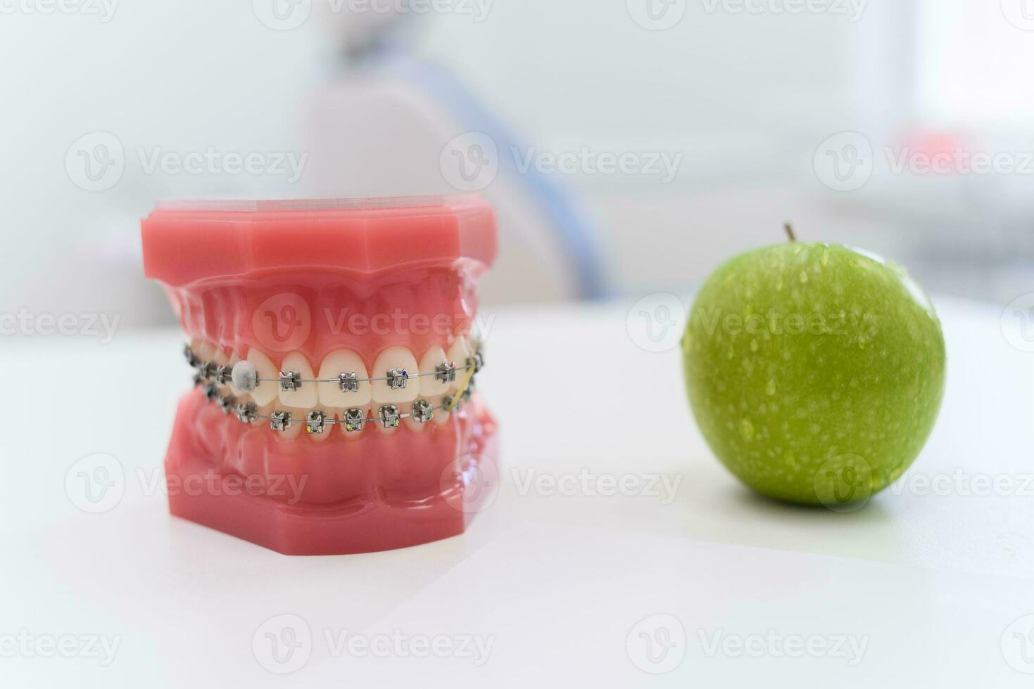 artificiell käftar med tandställning lögn med en grön äpple på de tabell foto