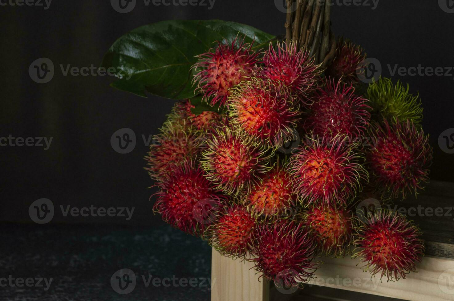 en knippa av rambutan frukt på en trä- hylla foto