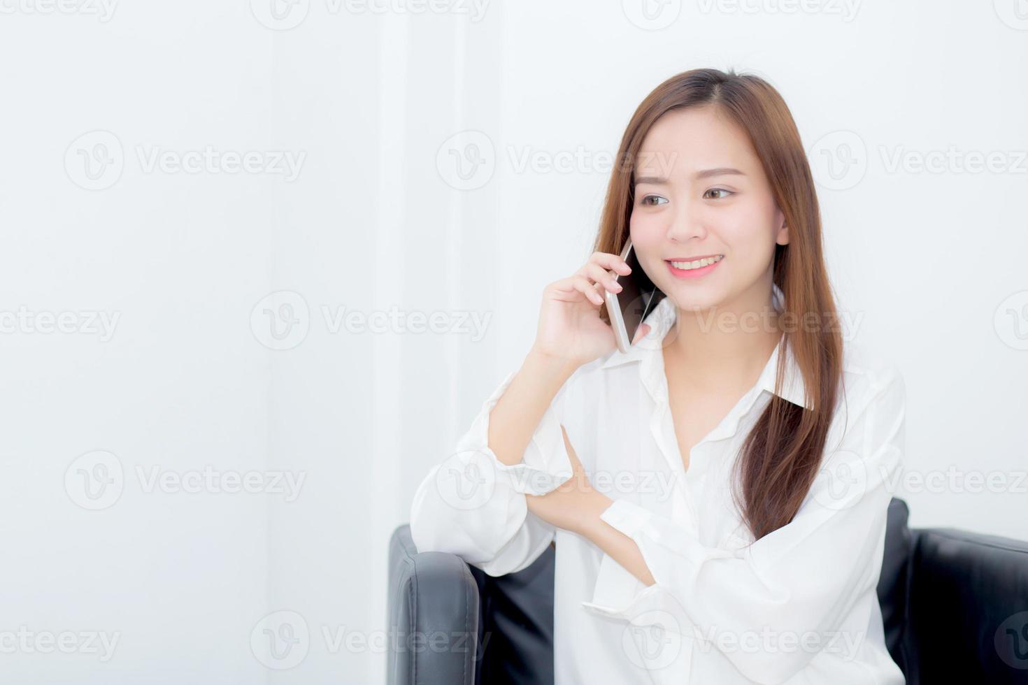 ung asiatisk kvinna som talar i smart telefon på stolen. foto