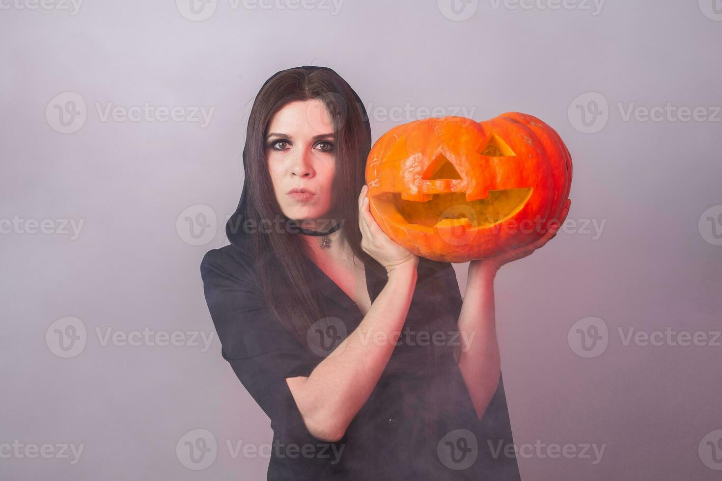 kvinna som häxa är stående med de pumpa i de studio. halloween och karneval begrepp foto