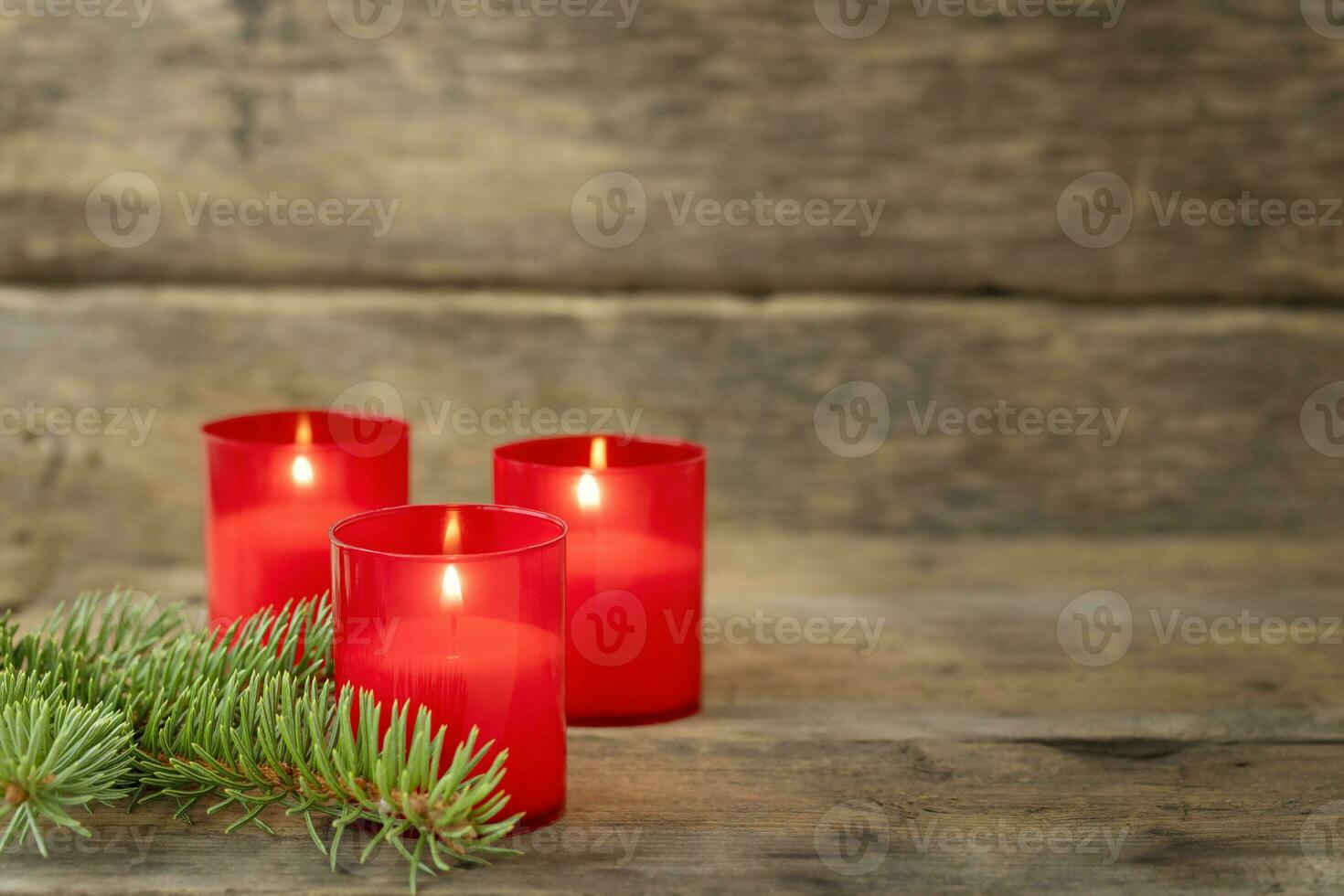 tre röd ljus och kvist av gran på trä- bakgrund foto