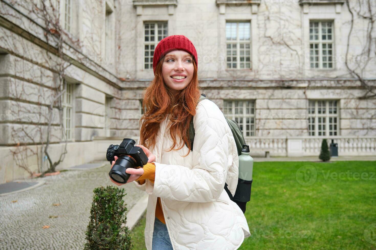 Lycklig rödhårig flicka turist, tar foton, fotograf med professionell kamera promenader runt om stad och fångar skön bilder foto