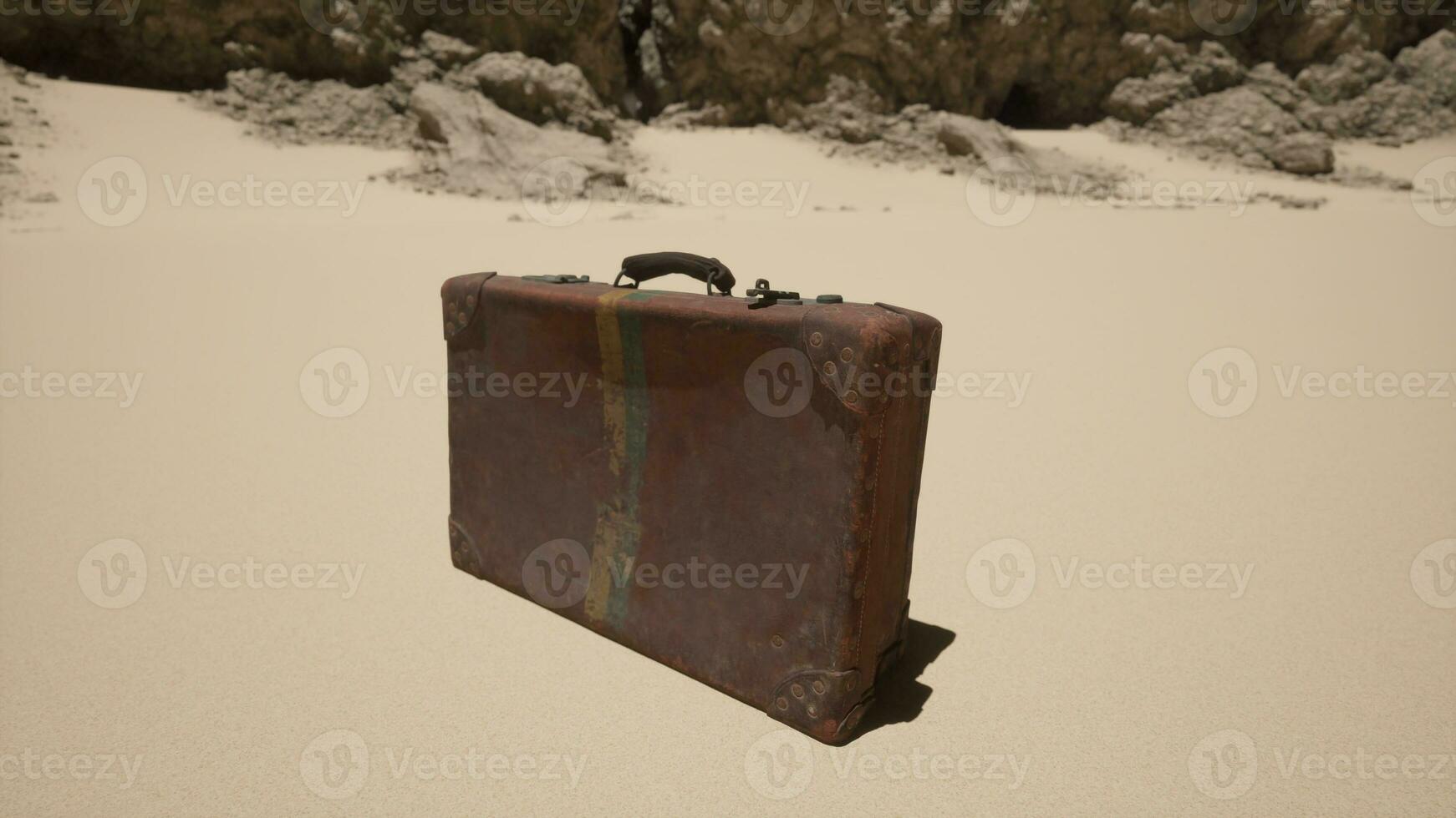 en bit av bagage Sammanträde på topp av en sandig strand foto