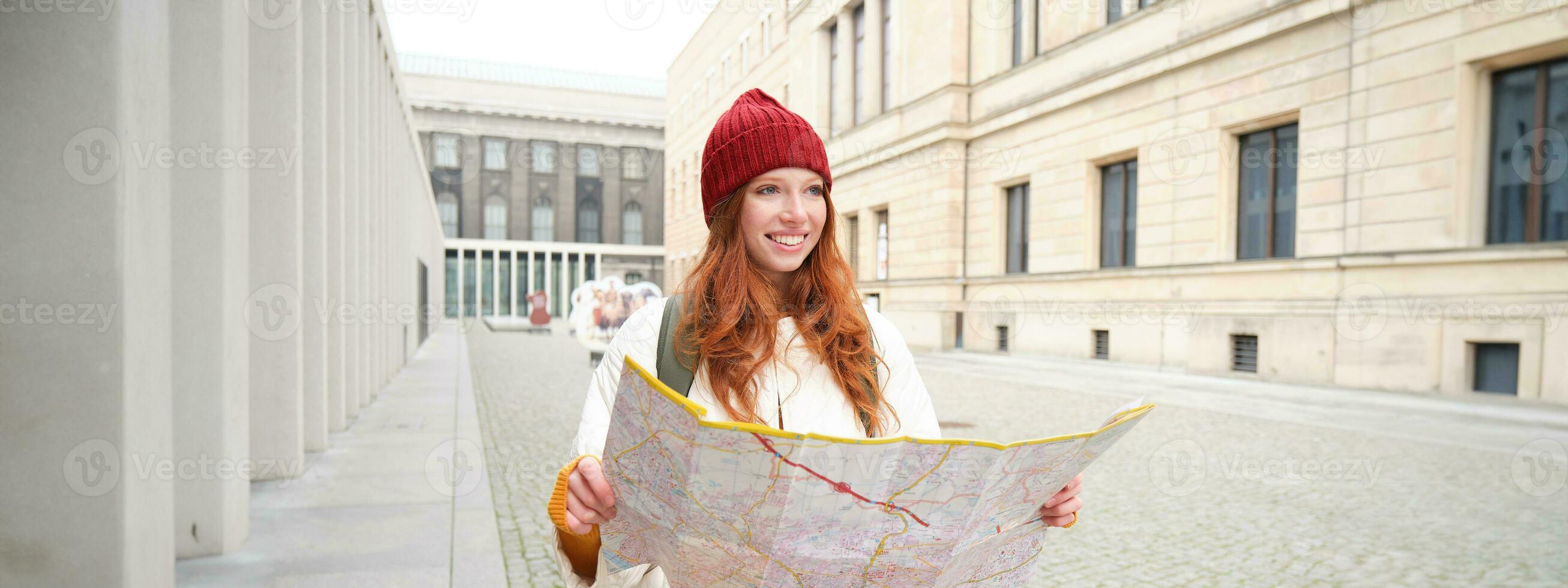 rödhårig flicka, turist utforskar stad, utseende på papper Karta till hitta sätt för historisk landmärken, kvinna på henne resa runt om euope sökningar för sightseeing foto