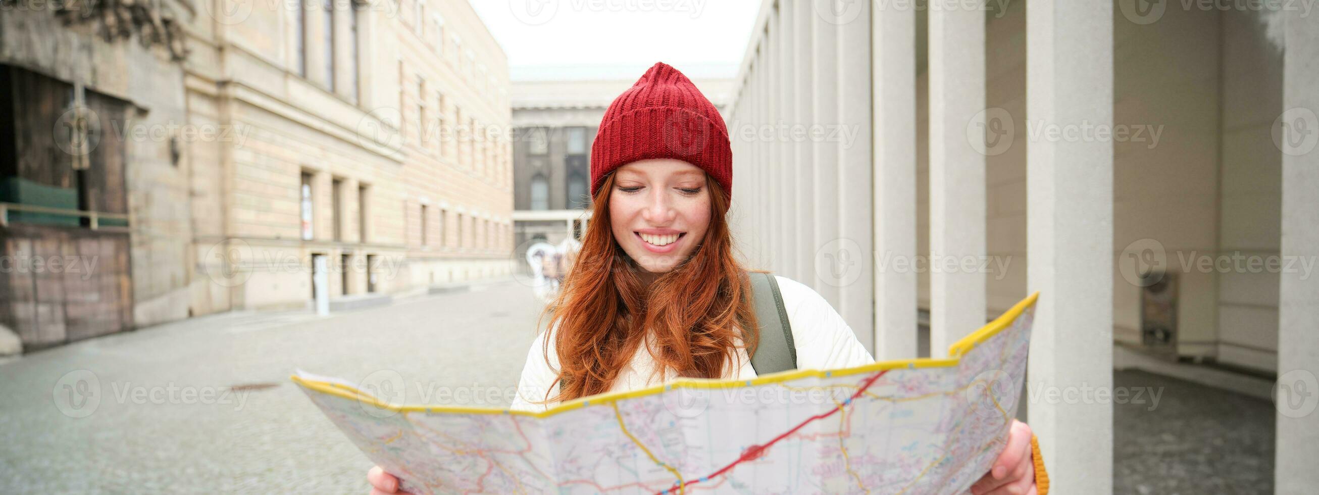 rödhårig flicka, turist utforskar stad, utseende på papper Karta till hitta sätt för historisk landmärken, kvinna på henne resa runt om euope sökningar för sightseeing foto