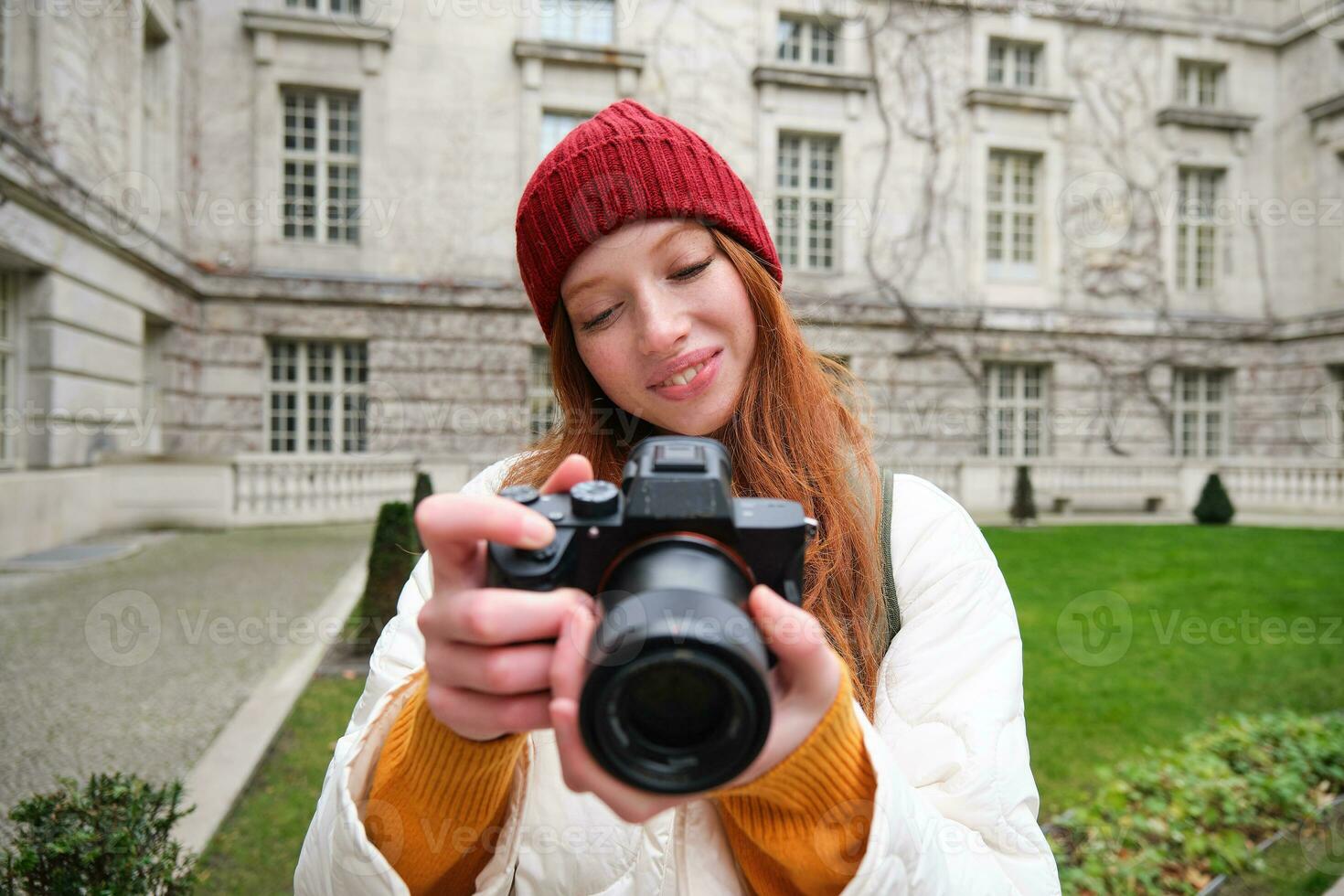 Lycklig rödhårig flicka turist, tar foton, fotograf med professionell kamera promenader runt om stad och fångar skön bilder foto