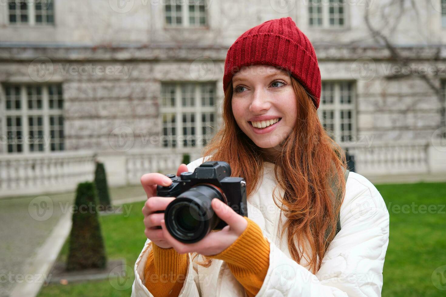 Lycklig rödhårig flicka turist, tar foton, fotograf med professionell kamera promenader runt om stad och fångar skön bilder foto