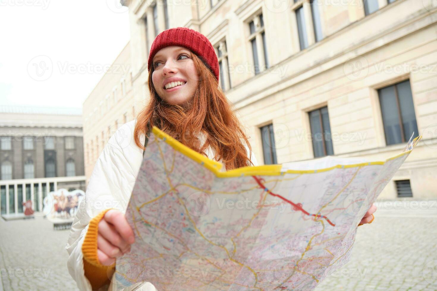 rödhårig flicka, turist utforskar stad, utseende på papper Karta till hitta sätt för historisk landmärken, kvinna på henne resa runt om euope sökningar för sightseeing foto