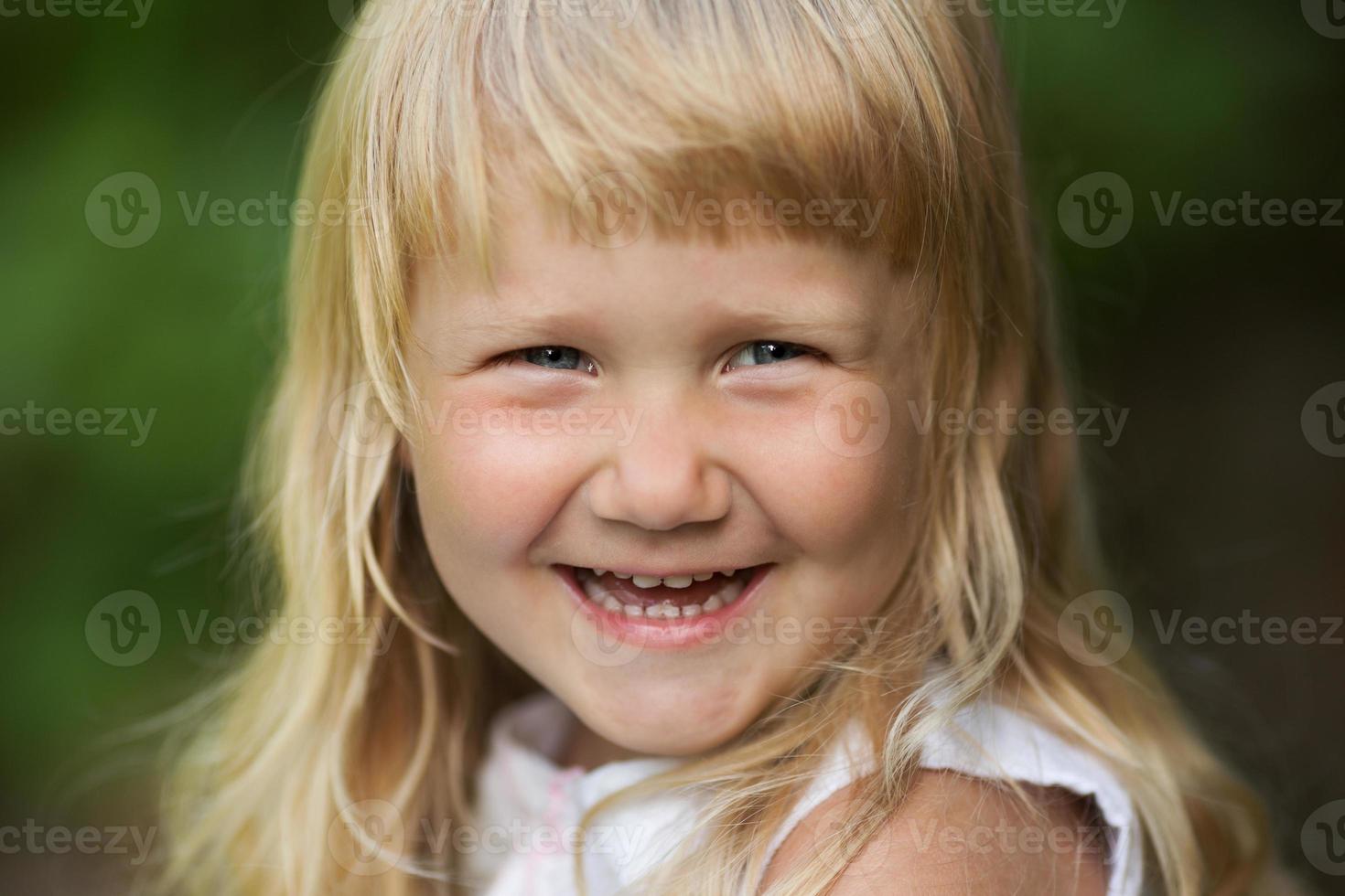 glad liten blond tjej ler glatt foto