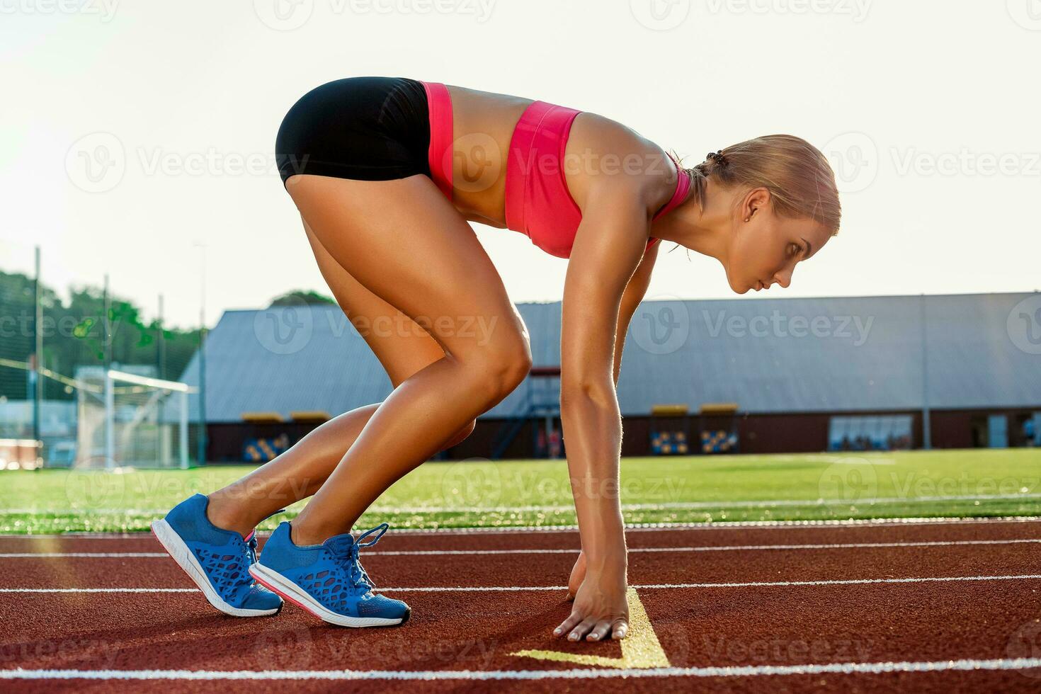 ung kvinna idrottare på startande placera redo till Start en lopp på racerbana. foto