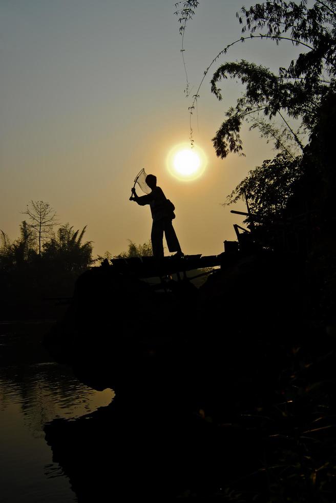 pojken står på ponton och fiskar foto