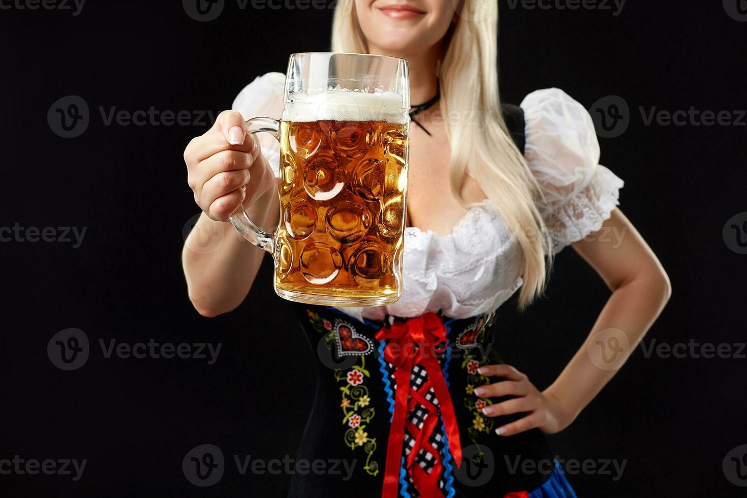 ung sexig kvinna bär en dirndl med öl råna på svart bakgrund. foto