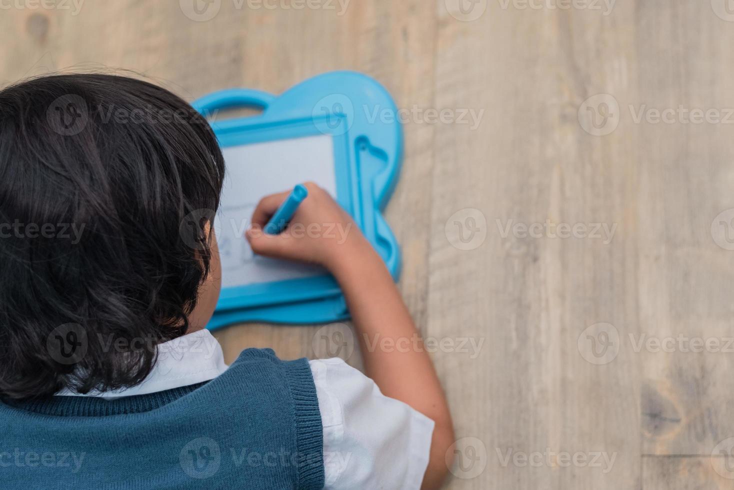 liten pojke ritning skiss i ritbord på hemskolan. utbildning och tillbaka till skolan koncept. barn utveckling tema. toppvy foto