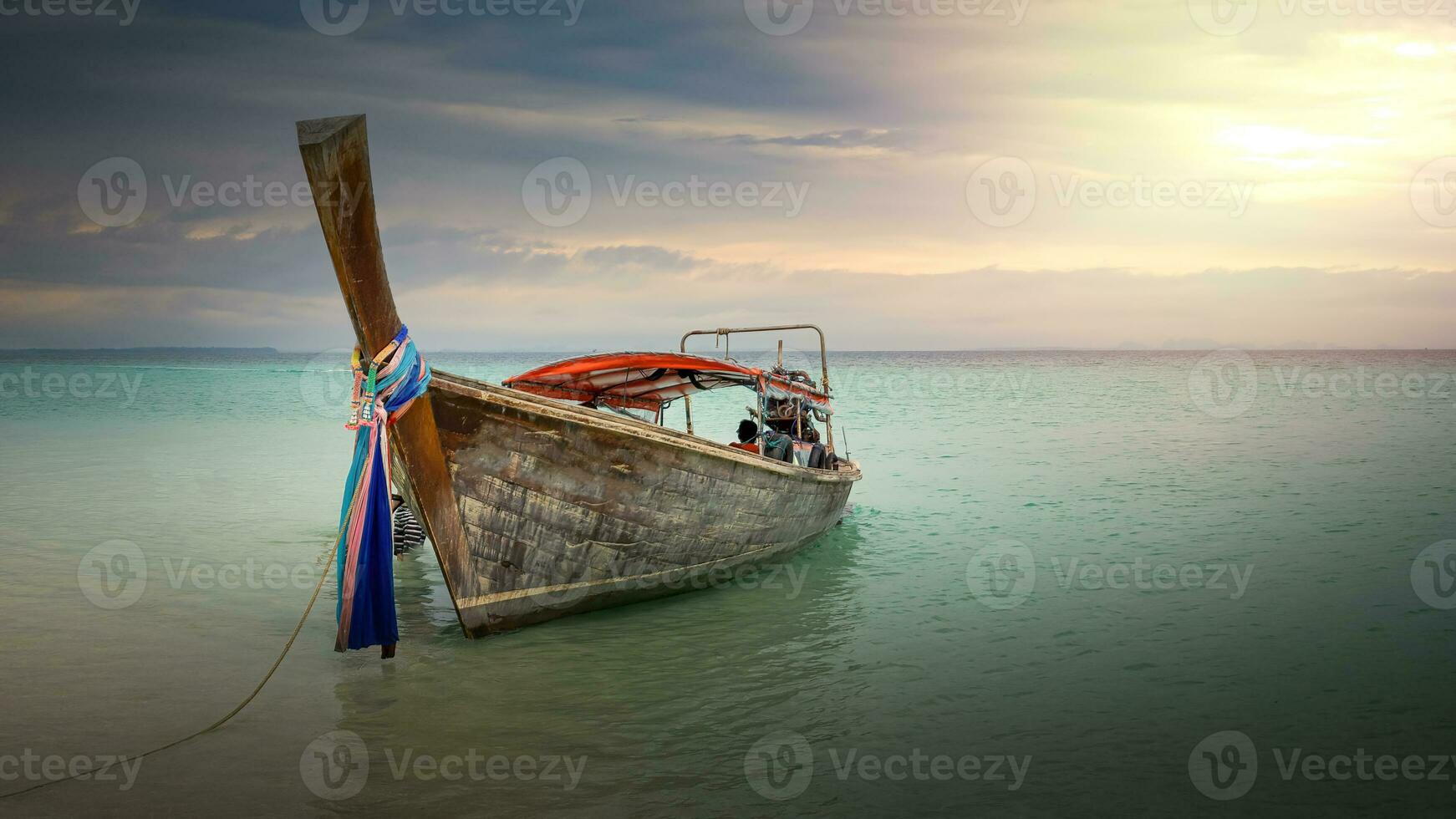 lång svans båt på en strand i thailand på solnedgång foto