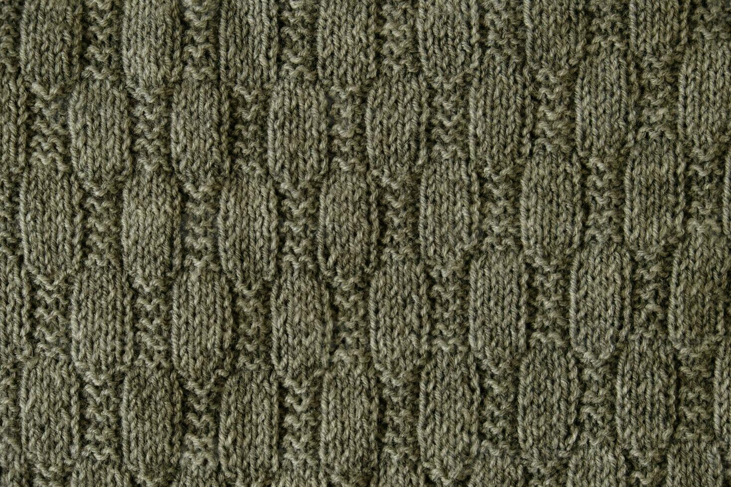 textur av slät stickat grå Tröja med mönster. topp se, närbild. handgjort stickning ull eller bomull tyg textur. bakgrund med stickat blad form, stickning mönster med kablar. foto