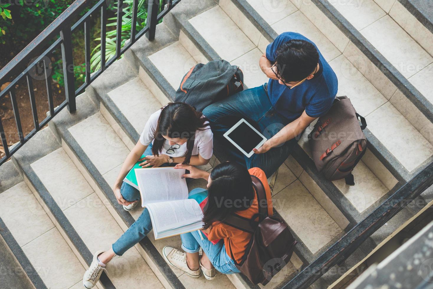 grupp asiatiska studenter använder surfplatta och mobiltelefon utanför klassrummet. lycka och utbildning inlärningskoncept. tillbaka till skolan koncept. tonåring och människor tema. tema utomhus och teknik foto