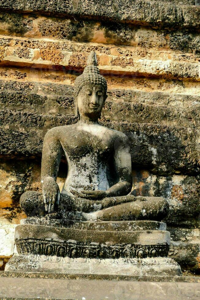 en buddha staty är Sammanträde på en sten vägg foto