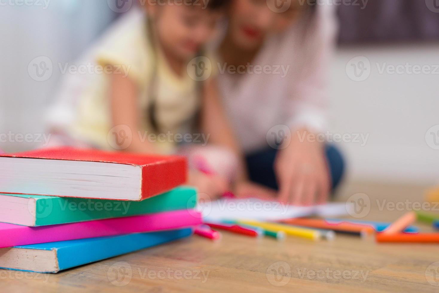 närbild av böcker och krita färg på golvet med mamma och barn bakgrund. tillbaka till skolan och konstutbildning inlärningskoncept. barn och lärartema foto