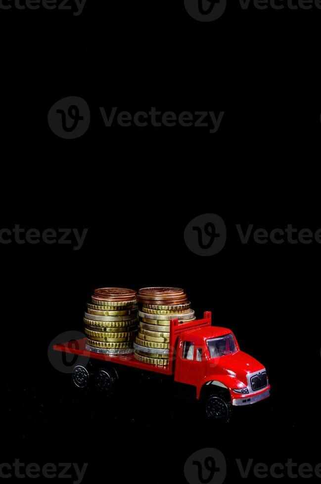 en röd lastbil med stackar av mynt på den foto