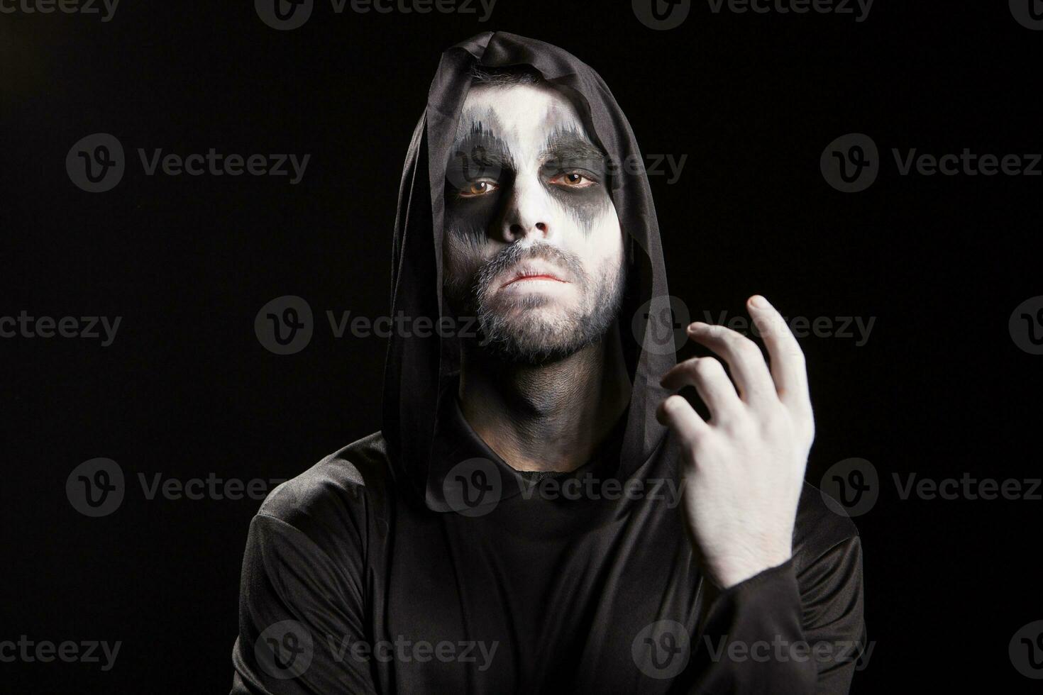 läskigt man klädd upp tycka om en dyster skördeman över svart bakgrund. halloween mysterium. foto