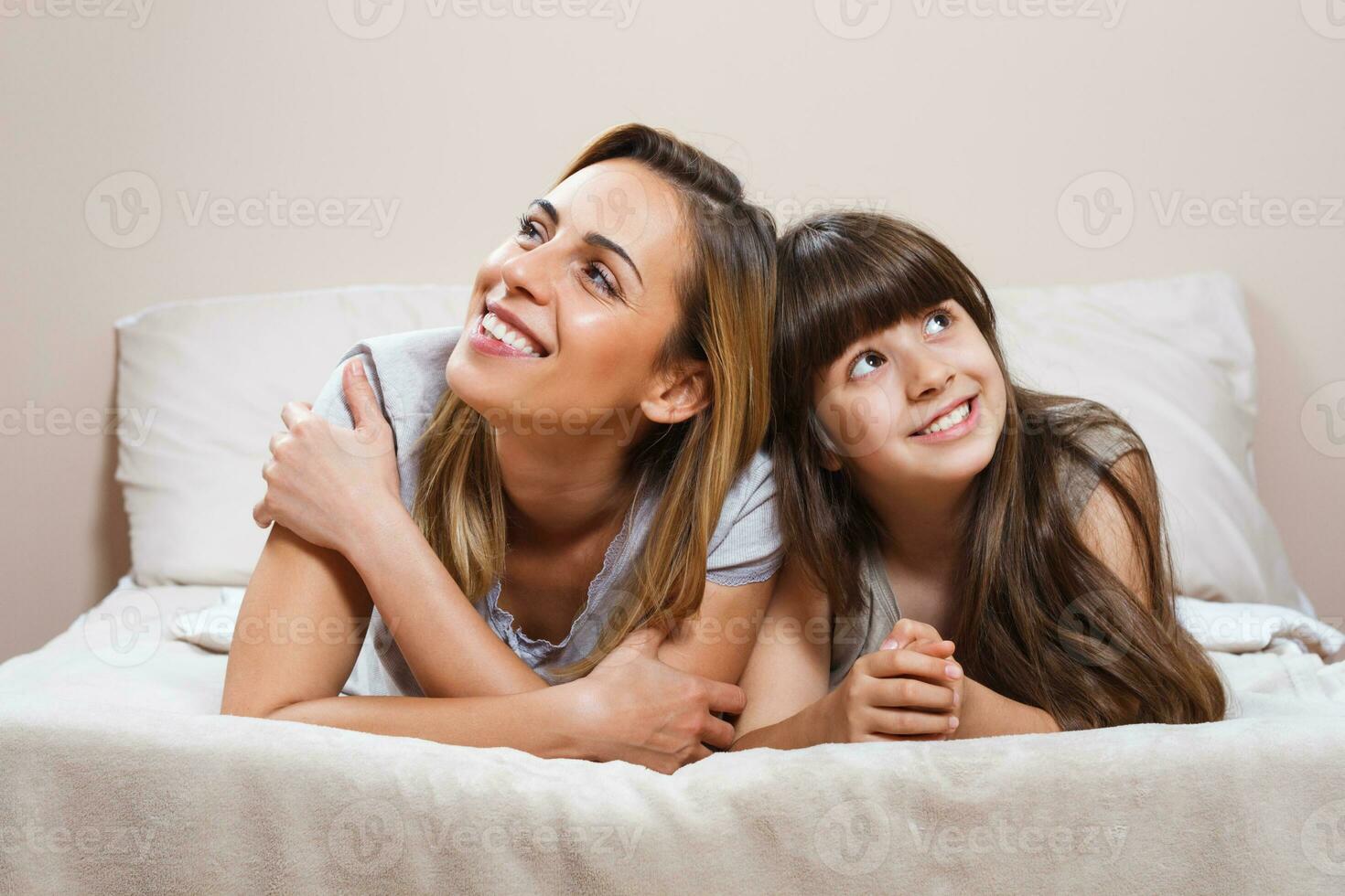 Lycklig mor och dotter liggande i säng foto