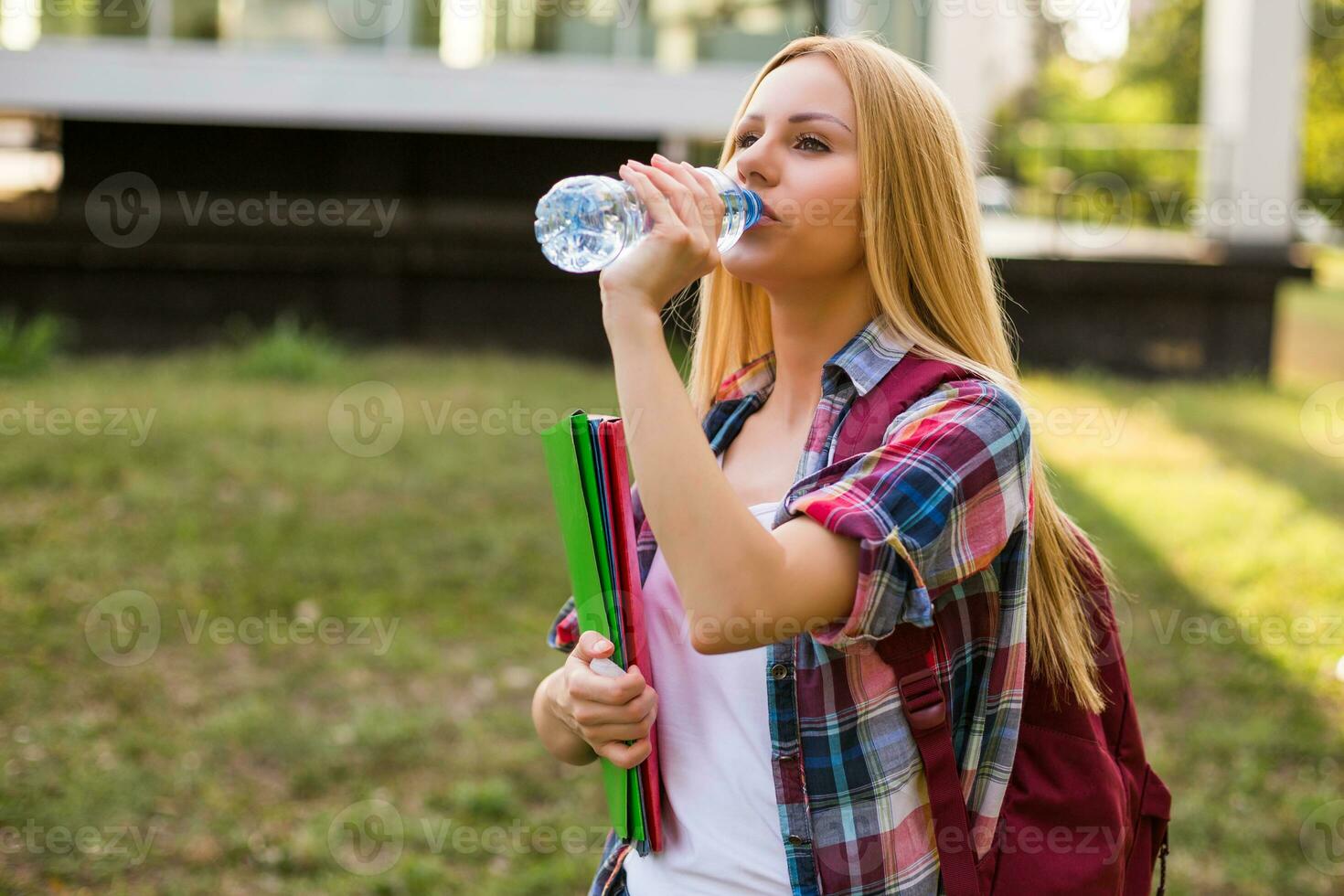 kvinna studerande dricka vatten medan stående utomhus. foto