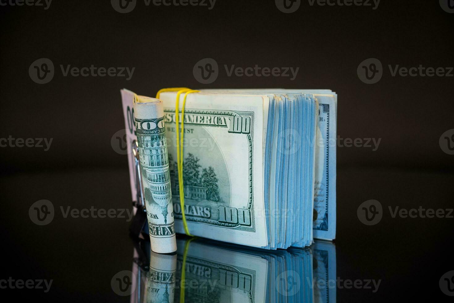 stack av dollar räkningar samlade in i ett elastisk band och en brevpapper klämma foto