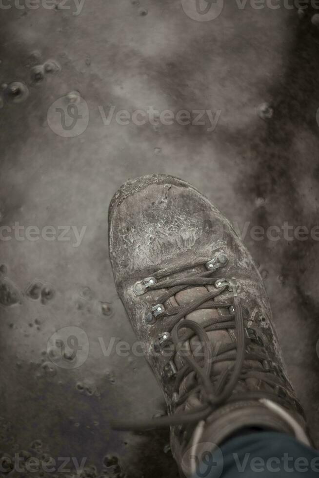 vertikal skott av vandring känga stepping in i lera foto
