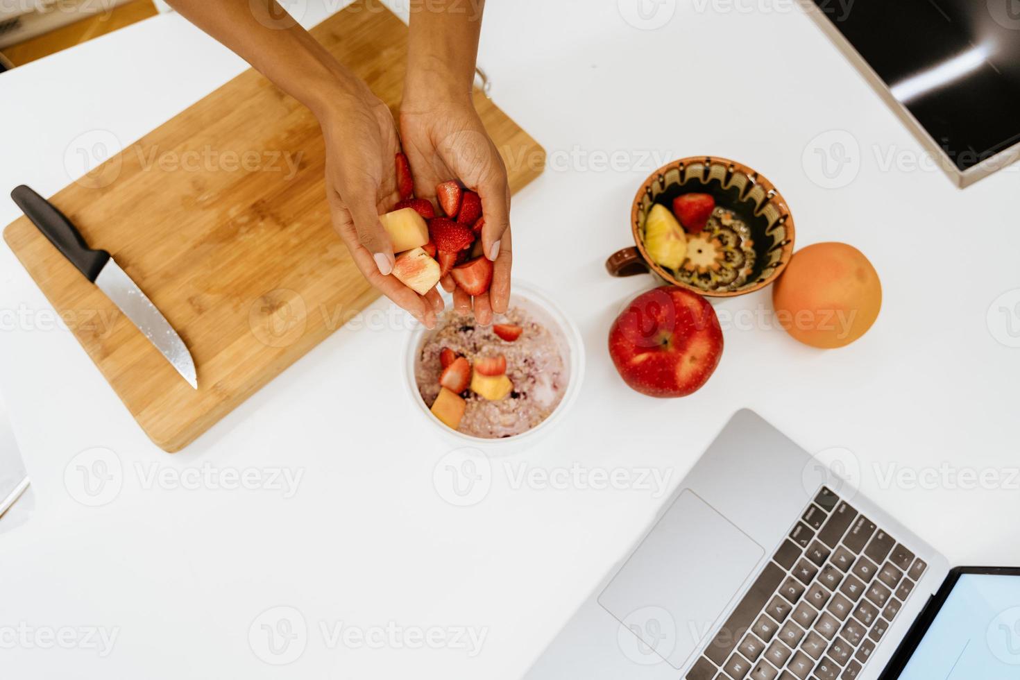 svart ung kvinna som gör spannmål med frukt i köket foto