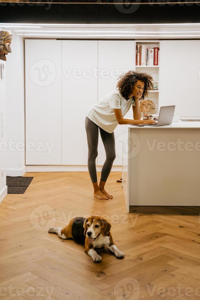 svart ung kvinna som använder bärbar dator medan hon står hemma foto