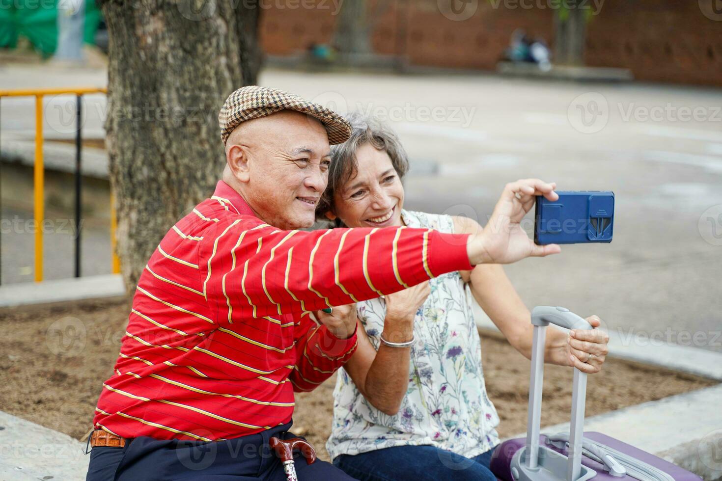 senior kinesisk turist med hans vän europeisk poser Lycklig och ta en Foto selfie på suddig av stad bakgrund. senior turist begrepp