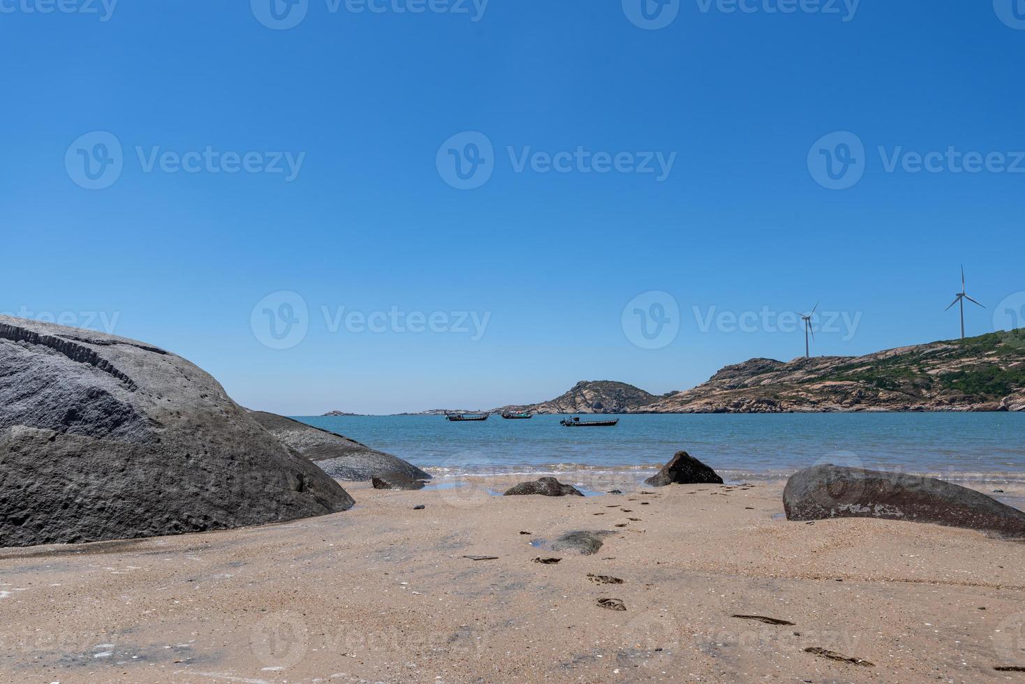 havet under den blå himlen, rena stränder och havsvatten, liksom öar och väderkvarnar foto