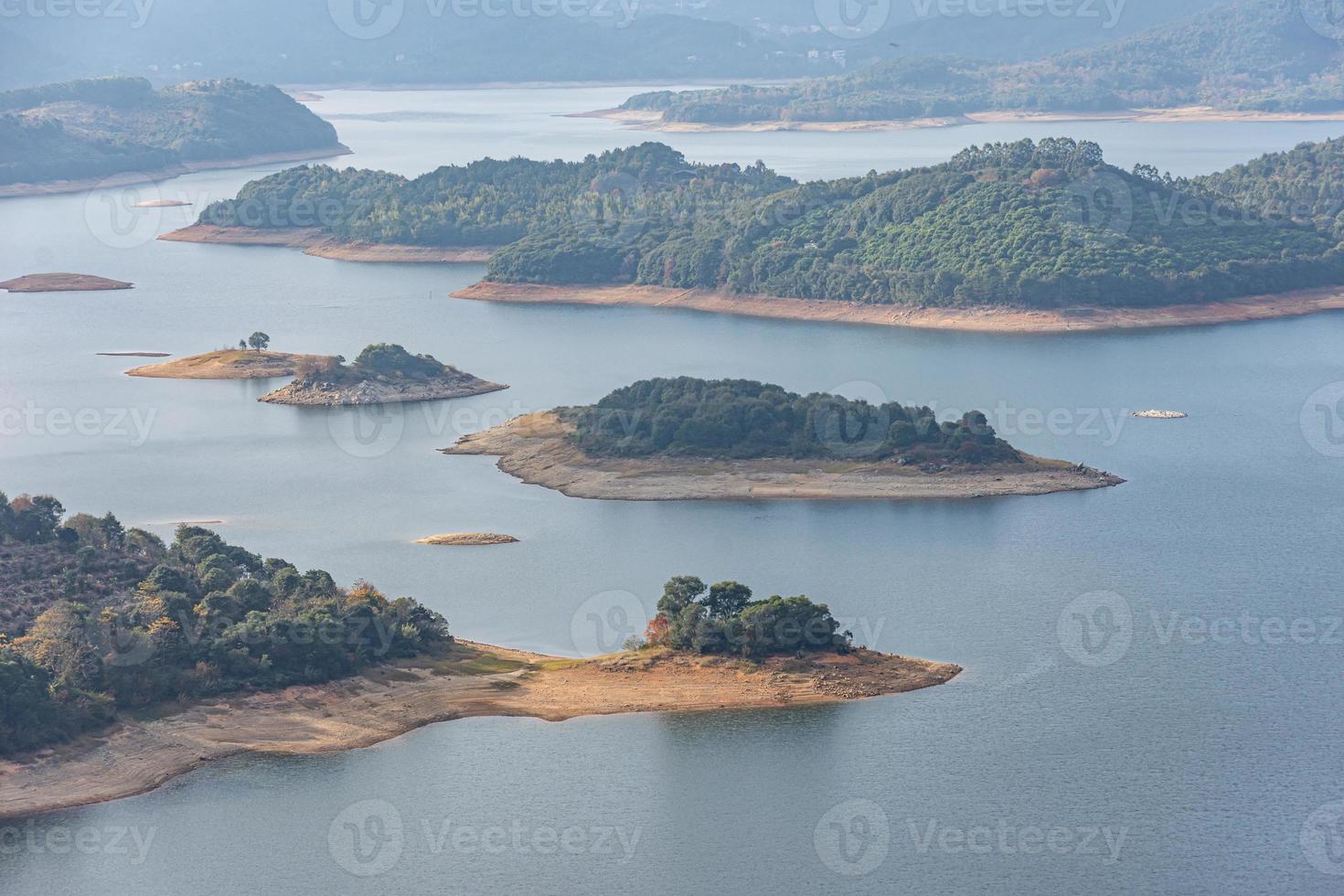 reservoaren under den blå himlen och de vita molnen omges av berg och skogar foto