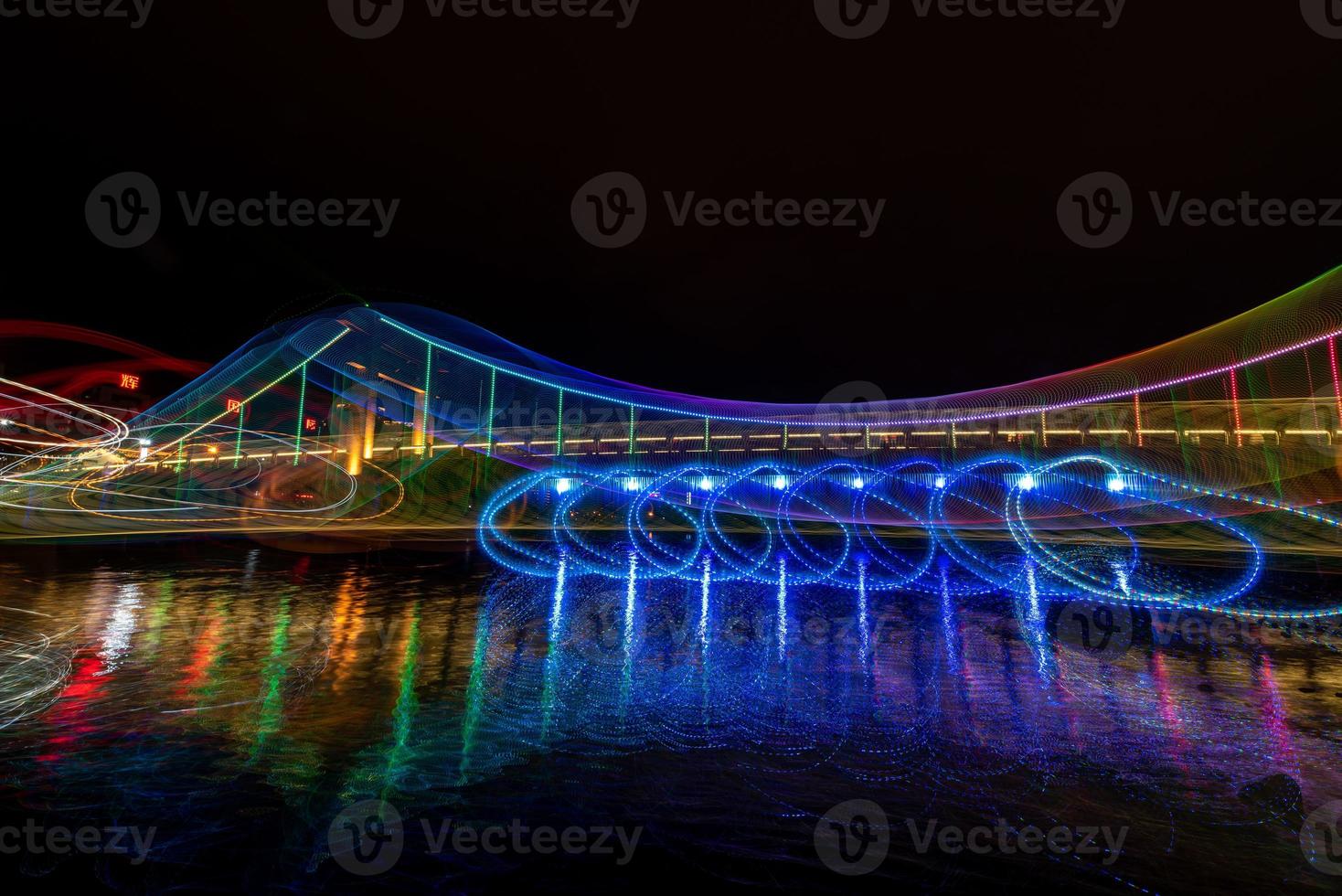 på natten reflekterar bäcken de färgglada ljusen på bron foto