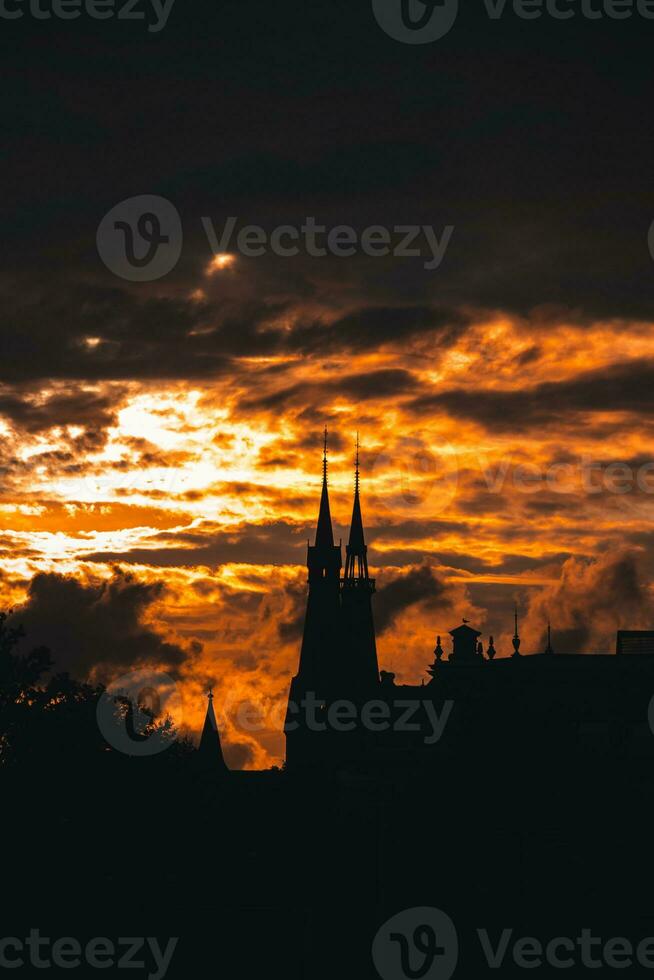 stormig och dramatisk solnedgång och silhuetter av de katedral spira i amsterdam, nederländerna foto