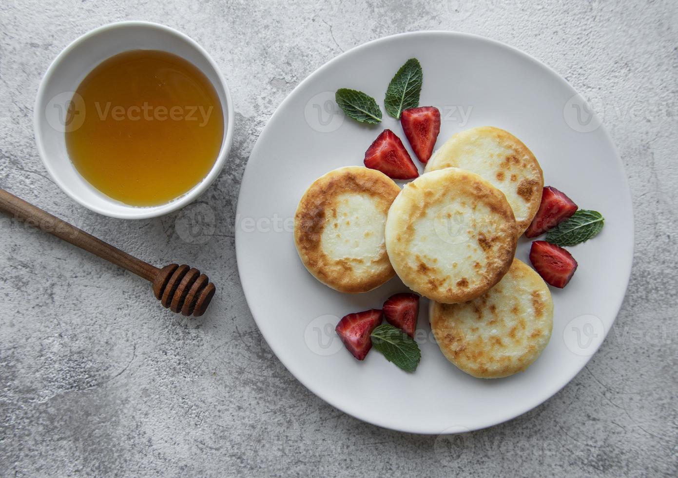 keso, pannkakor, ricottafritter på keramisk tallrik med färsk jordgubbe foto