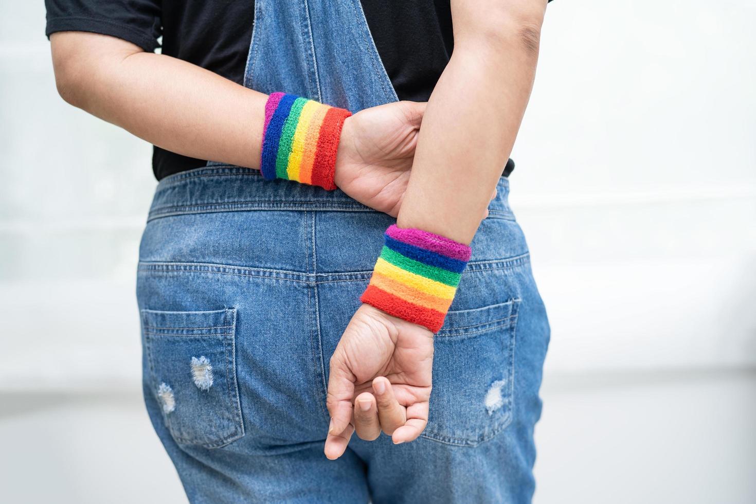 asiatisk dam som bär regnbågsflaggarmband, symbol för lgbt pride -månad firar årligen i juni social av homosexuella, lesbiska, bisexuella, transpersoner, mänskliga rättigheter foto