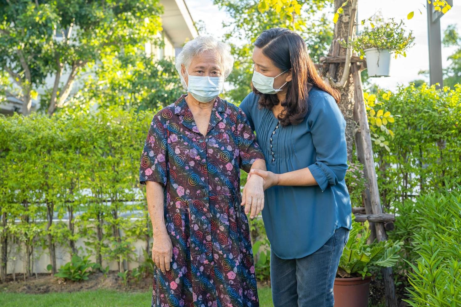 asiatisk äldre kvinna med vårdgivare som går med glad i naturparken foto