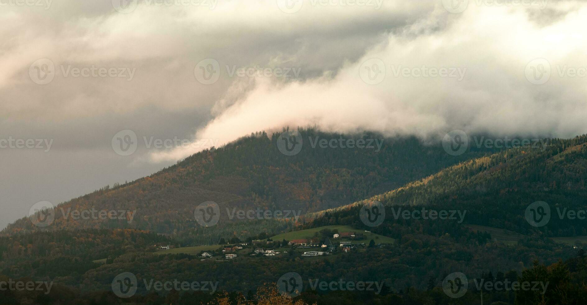 beatiful skott av en små by på en berg med moln strömmande över foto