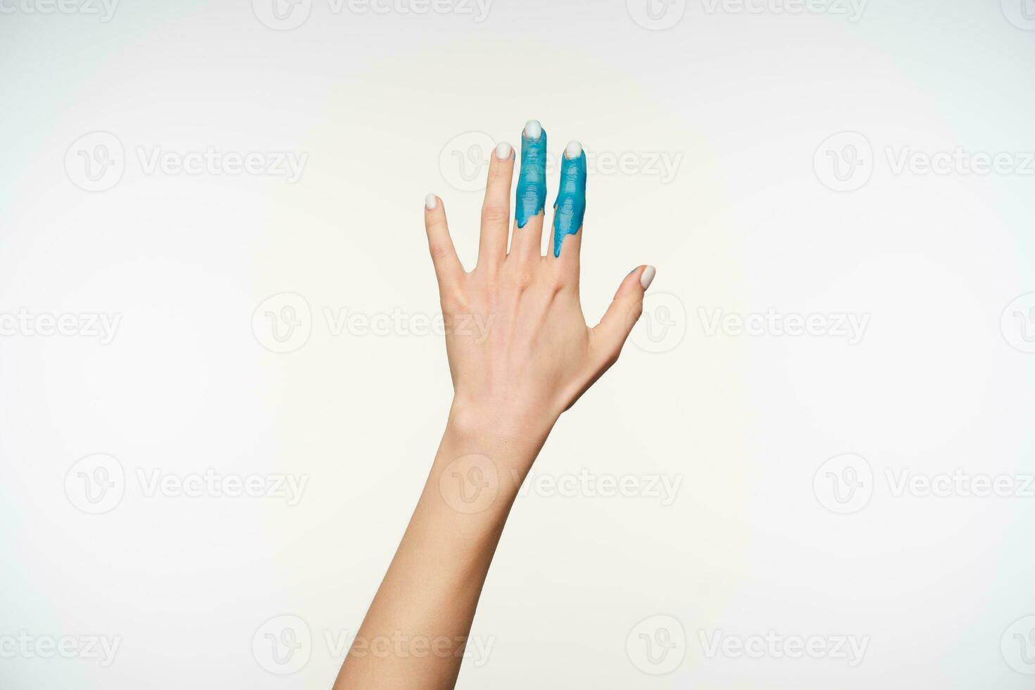 studio Foto av elegant kvinnas Uppfostrad hand med blå måla på pekfinger och mitten finger dragande den ett huvud medan varelse isolerat över vit bakgrund
